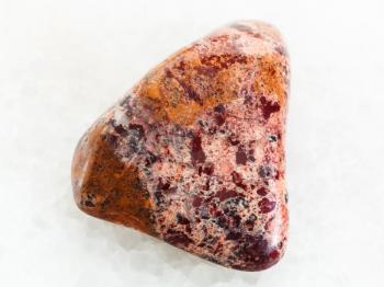 macro shooting of natural mineral rock specimen - tumbled Brecciated Jasper stone on white marble background from Ural Mountains, Russia