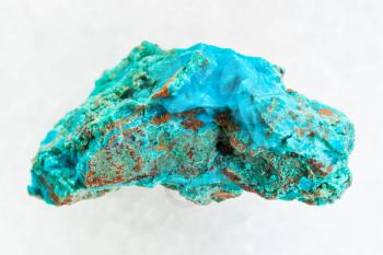 macro shooting of natural mineral rock specimen - rough Chrysocolla stone in copper sandstone on white marble background from Zabaykalsky Krai of Russia