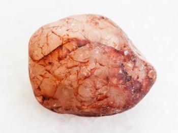 macro shooting of natural mineral rock specimen - pebble of pink quartz stone on white marble background
