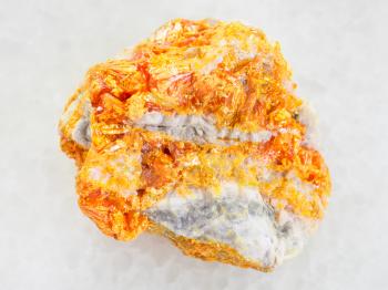 macro shooting of natural mineral rock specimen - raw yellow Orpiment crystals on white dolomite stone on white marble background from Kabardino-Balkarian Republic, Northern Caucasus Region, Russia