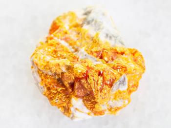 macro shooting of natural mineral rock specimen - rough yellow Orpiment crystals on white dolomite stone on white marble background from Kabardino-Balkarian Republic, Northern Caucasus Region, Russia