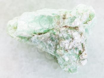 macro shooting of natural mineral rock specimen - rough green talc stone on white marble background from Shabrovsky (Shabry) district of Sverdlovk region, Ural Mountains, Russia