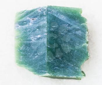 macro shooting of natural mineral rock specimen - rough nephrite stone slab on white marble background