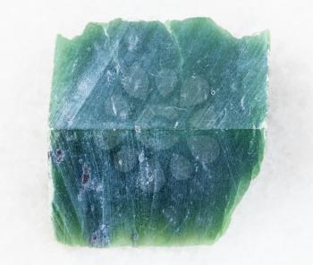 macro shooting of natural mineral rock specimen - raw nephrite stone slab on white marble background