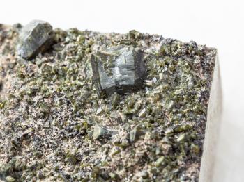 macro shooting of natural mineral stone specimen - crystals of Epidote close up on white marble background from Irkutsk region, Russia