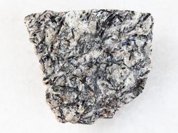 macro shooting of natural mineral rock specimen - raw lujavrite stone on white marble background from Lovozero Massif, Kola Peninsula, Russia