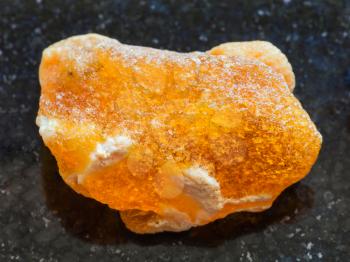 macro shooting of natural mineral rock specimen - raw baltic Amber stone on dark granite background from Latvia