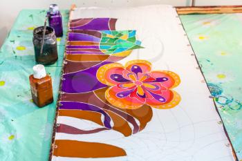 batik painting on silk fabric stretched on wooden frame in workshop