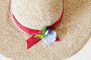 above view of ladies' wide brim straw hat with red band and textile flower