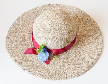 ladies' wide brim straw hat with red band and textile flower on white background