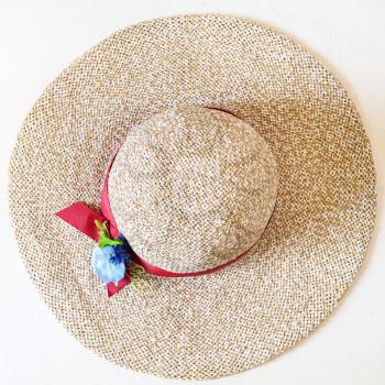 top view of ladies' wide brim straw hat with red band and textile flower on white background