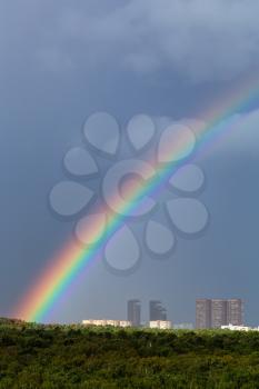 rainbow in rain over Moscow city and green trees in Timiryazevskiy urban park