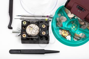 watchmaker workshop - tools with head-mounted magnifier and spare parts close up for repairing mechanical watch on white background