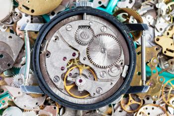 watchmaker workshop - open vintage wristwatch on heap of clock spare parts