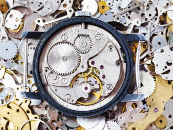watchmaker workshop - open used mechanical watch on heap of clock spare parts