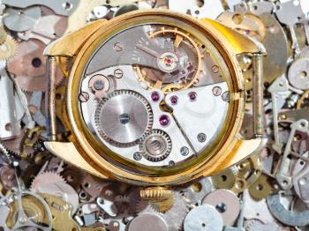 watchmaker workshop - open old golden mechanical wristwatch on heap of clock spare parts