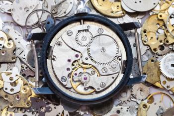 watchmaker workshop - open used mechanical wristwatch on heap of clock spare parts