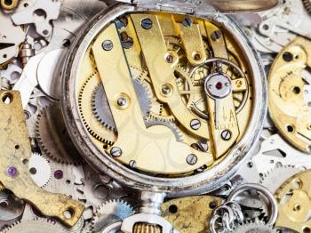 watchmaker workshop - open old brass mechanical pocket watch on pile of clock spare parts