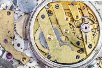 watchmaker workshop - open old brass mechanical watch on pile of clock spare parts