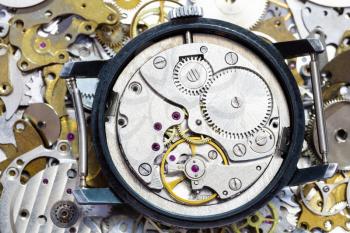 watchmaker workshop - open old mechanical watch on pile of clock spare parts