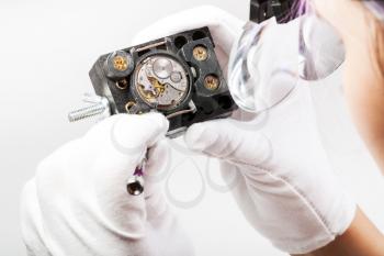watchmaker workshop - watchmaker in head-mounted magnifying glasses repairs old mechanical wristwatch with screwdriver
