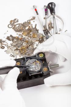 watchmaker workshop - repair of mechanic watch with spare parts by tweezers on white background
