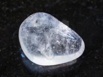 macro shooting of natural mineral rock specimen - tumbled Rock-crystal gemstone on dark granite background