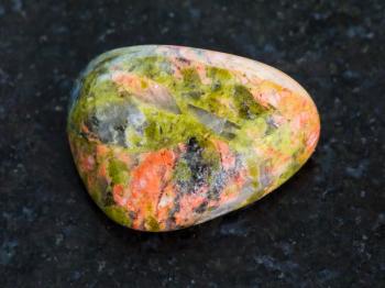 macro shooting of natural mineral rock specimen - polished Unakite gemstone on dark granite background
