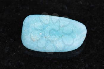 macro shooting of natural mineral rock specimen - tumbled Aquamarine (blue beryl) gemstone on dark granite background