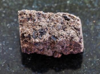 macro shooting of natural mineral rock specimen - rough Peat Turf stone on dark granite background