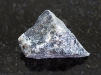 macro shooting of natural mineral rock specimen - rough stibnite (antimonite) ore on dark granite background