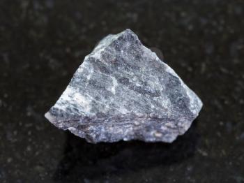 macro shooting of natural mineral rock specimen - raw stibnite (antimonite) ore on dark granite background