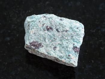 macro shooting of natural mineral rock specimen - raw Trachyte stone on dark granite background