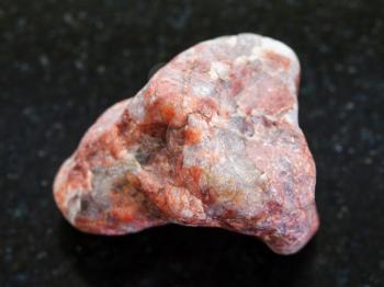 macro shooting of natural mineral rock specimen - piece of Pegmatite stone on dark granite background
