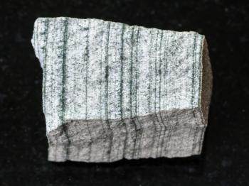 macro shooting of natural mineral rock specimen - rough Skarn stone on dark granite background from Primorsky Krai, Russia
