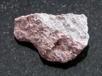 macro shooting of natural mineral rock specimen - rough Ash Tuff stone on dark granite background