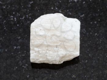 macro shooting of natural mineral rock specimen - white Gypsum stone on dark granite background