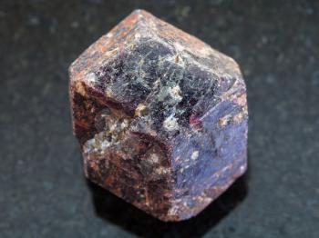 macro shooting of natural mineral rock specimen - rough crystal of dravite tourmaline gemstone on dark granite background from China