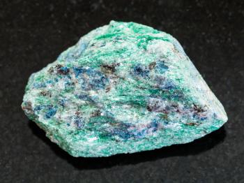 macro shooting of natural mineral rock specimen - raw Fuchsite (chrome mica) stone on dark granite background from Hizovaara, Republic of Karelia in Russia
