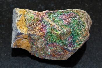 macro shooting of natural mineral rock specimen - rough rainbow pyrite stone on dark granite background from Ulyanovsk region, Russia