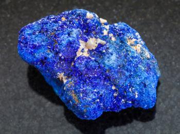 macro shooting of natural mineral rock specimen - raw crystalline Azurite stone on dark granite background from Rubtsovskiy mine, Altai Mountains, Russia