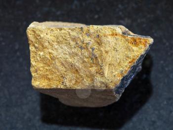 macro shooting of natural mineral rock specimen - raw yellow Chalcopyrite stone on dark granite background from Safyanovskoe mine, Sverdlovsk region, Ural Mountains, Russia
