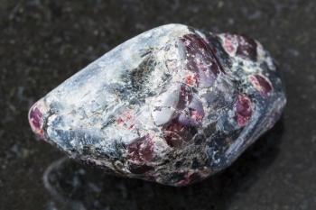 macro shooting of natural mineral rock specimen - tumbled Almandine garnet and biotite crystals in gemstone on dark granite background from Yelovyy Navolok (Shuyeretskoye) mine in Karelia, Russia