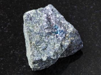 macro shooting of natural mineral rock specimen - rough bornite stone on dark granite background from Azerbaijan