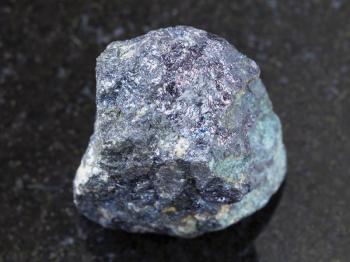macro shooting of natural mineral rock specimen - bornite stone on dark granite background from Azerbaijan