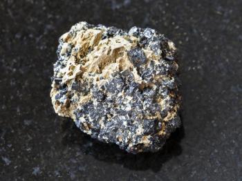 macro shooting of natural mineral rock specimen - raw Perovskite stone on dark granite background