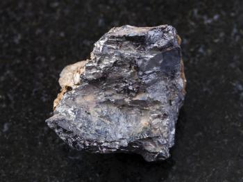 macro shooting of natural mineral rock specimen - rough ilmenorutile (Nb-bearing rutile) stone on dark granite background from South Ural Mountains, Russia