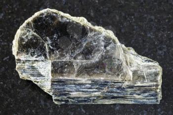 macro shooting of natural mineral rock specimen - rough muscovite mica stone on dark granite background from Pirtima mine, Karelia, Russia
