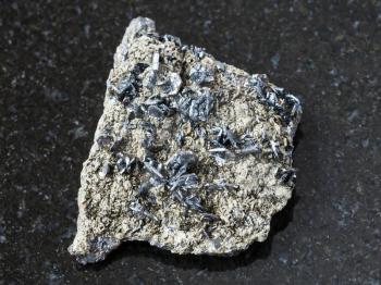 macro shooting of natural mineral rock specimen - magnetite crystals on rough stone on dark granite background from Korshunovskoe mine, Irkutsk region, Russia