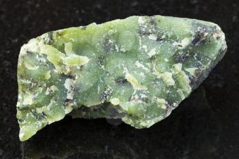 macro shooting of natural mineral rock specimen - raw Lizardite stone on dark granite background from Saranovskoe mine, Ural Mountains, Russia